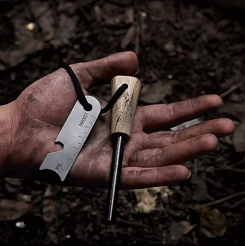 Survival-Feuerstarter von Armydropz.ch  mit Holzgriff, liegt in einer schmutzigen Hand im Wald beim Survival-Camping.